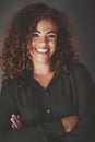 Smiling businesswoman standing with arms crossed against a gray Royalty Free Stock Photo