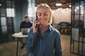 Smiling businesswoman standing in an office talking on her cellp