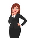 Smiling businesswoman standing, touching finger to cheek with folded or crossed arms in formal black suit. Royalty Free Stock Photo
