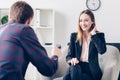 Smiling businesswoman in suit touching hair while giving interview to journalist Royalty Free Stock Photo