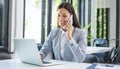 Smiling businesswoman talking on mobile phone and using laptop in office Royalty Free Stock Photo