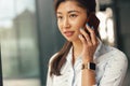 Smiling businesswoman talking phone with client while standing in office and looking at side Royalty Free Stock Photo