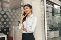 Smiling businesswoman talking phone with client while standing in office and looking at side Royalty Free Stock Photo