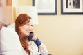 Smiling businesswoman talking on phone while sitting on the bed in hotel room. Royalty Free Stock Photo