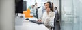 Smiling businesswoman using computer and listening to client via headset in call center office. Panoramic view Royalty Free Stock Photo