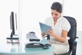 Smiling businesswoman using her digital tablet at desk Royalty Free Stock Photo