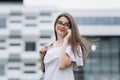 Smiling businesswoman using her mobile phone. Cheerful attractive young businesswoman in glasses standing and using Royalty Free Stock Photo