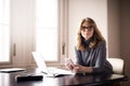 Smiling businesswoman using her mobile phone and text messaging while working from home Royalty Free Stock Photo