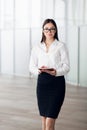 Smiling businesswoman walking along the office corridor with a tablet computer Royalty Free Stock Photo