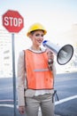 Smiling businesswoman wearing builders clothes shouting in megaphone Royalty Free Stock Photo