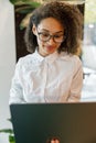 African businesswoman working laptop while standing near window in coworking Royalty Free Stock Photo