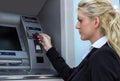 Businesswoman withdrawing money from credit card at ATM