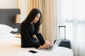 Smiling businesswoman working on laptop computer in bed at hotel. Business trip, people and technology concept, copy space Royalty Free Stock Photo