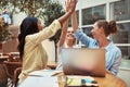 Smiling businesswomen high fiving together in an office lounge Royalty Free Stock Photo