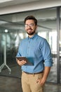Smiling young business man manager with tab standing in office. Portrait. Royalty Free Stock Photo