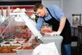 Smiling butcher standing in butcher shop with tray of fresh raw meat steak cutlets Royalty Free Stock Photo