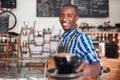 Smiling cafe barista offering up a fresh cup of cappuccino Royalty Free Stock Photo