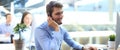 Smiling call center employees sitting in line with their headset. Royalty Free Stock Photo