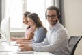 Smiling call center worker sitting at workplace looking at camera