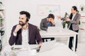 Smiling call center operator sitting at desk with brawling colleagues Royalty Free Stock Photo