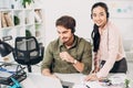 Smiling call center operator working at laptop and pretty coworker looking at camera Royalty Free Stock Photo