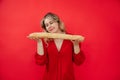 Smiling calm attractive blonde woman in red clothes hold gently and smell french bread baguette in hands in red studio