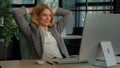 Smiling calm relaxed resting business woman finished computer work stretching sitting at desk in office. Happy middle Royalty Free Stock Photo