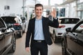 Smiling car dealer showing okay gesture, standing among new automobiles, recommending modern auto dealership Royalty Free Stock Photo