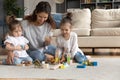 Smiling caring mother playing with two little daughters on floor Royalty Free Stock Photo