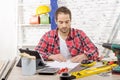 Smiling carpenter sitting at the desk, in his studio