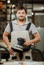 Smiling carpenter stand with eccentric grinding machine in hands Royalty Free Stock Photo