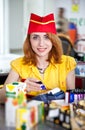 Smiling cashier girl in red and yellow uniform