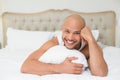 Smiling casual bald young man lying in bed