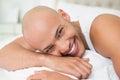 Smiling casual bald young man lying in bed