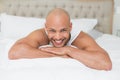 Smiling casual bald young man lying in bed