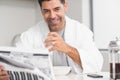 Smiling casual man with coffee cup reading newspaper in kitchen Royalty Free Stock Photo