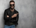 Smiling casual man wearing leather jacket points to side Royalty Free Stock Photo