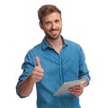 Smiling casual man working on tablet makes the ok sign