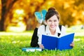 Smiling casual student lying on grass reading book Royalty Free Stock Photo