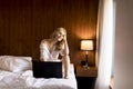 Smiling casual young woman using laptop in bed at home Royalty Free Stock Photo