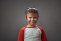 Smiling Caucasian boy with face mask wearing at his head. Happy Little boy posing on grey background.