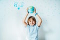 Smiling caucasian boy holding an earth globe model over his head on the background with stars and family hand prints on Royalty Free Stock Photo