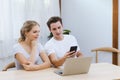 Smiling caucasian couple using smartphone for webinar or online shopping, surfing social media at home. Happy lover working Royalty Free Stock Photo