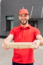 smiling caucasian delivery man holding box with pizza and looking Royalty Free Stock Photo
