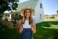 Smiling caucasian female farmer standing outdoors holding dungarees Royalty Free Stock Photo