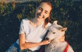 Smiling caucasian girl dressed in a white t-shirt is playing with her dog while lying on the grass in the park Royalty Free Stock Photo