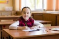 Smiling caucasian girl sitting at desk in class room and ready to study. Portrait of young pre schoolgirl. Happy pupil Royalty Free Stock Photo