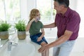 Smiling caucasian grandfather in bathroom with grandson brushing teeth sitting beside basin