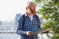 Smiling caucasian hipster bearded man having trip. Smiling male traveler walking with map on weekends. Travel concept Royalty Free Stock Photo