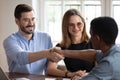 African American realtor handshake happy couple closing deal in office